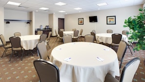 A conference room with round tables, chairs, and a television on the wall. - Holiday Inn Express & Suites Omaha I-80 by IHG (Gretna)