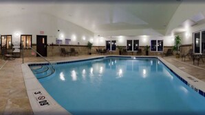An indoor swimming pool with clear lane markings, a tiled floor, and a seating area with chairs and tables. - Holiday Inn Express & Suites Omaha I-80 by IHG (Gretna)