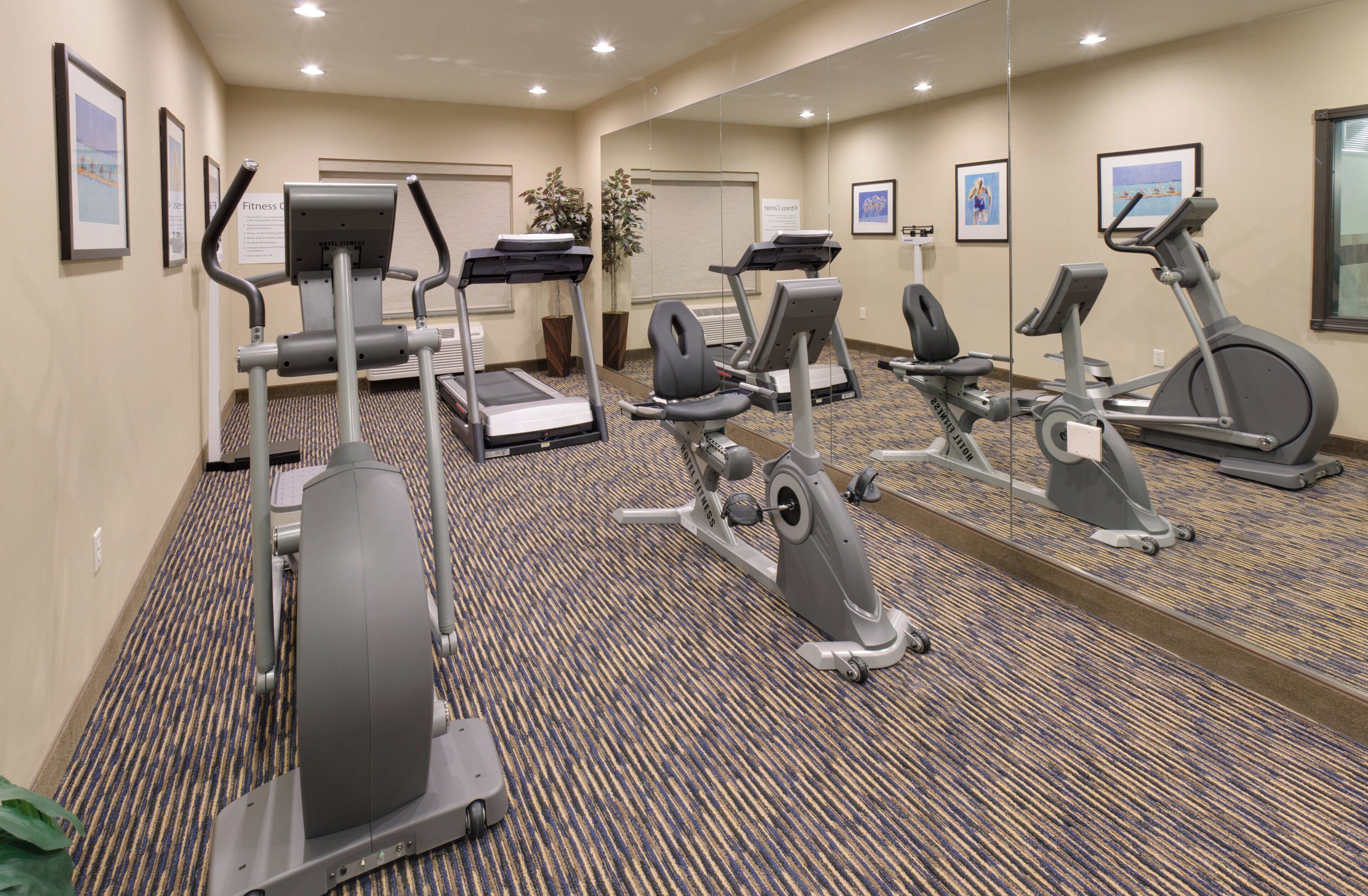 A hotel fitness center with treadmills, elliptical machines, and stationary bikes.