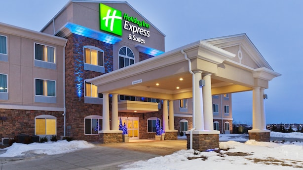 A Holiday Inn Express & Suites building with a brick facade, large windows, and a covered entrance area. - Holiday Inn Express & Suites Omaha I-80 by IHG (Gretna)