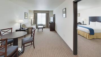 Habitación de hotel con cama, escritorio con silla, televisor y ventana con cortinas.