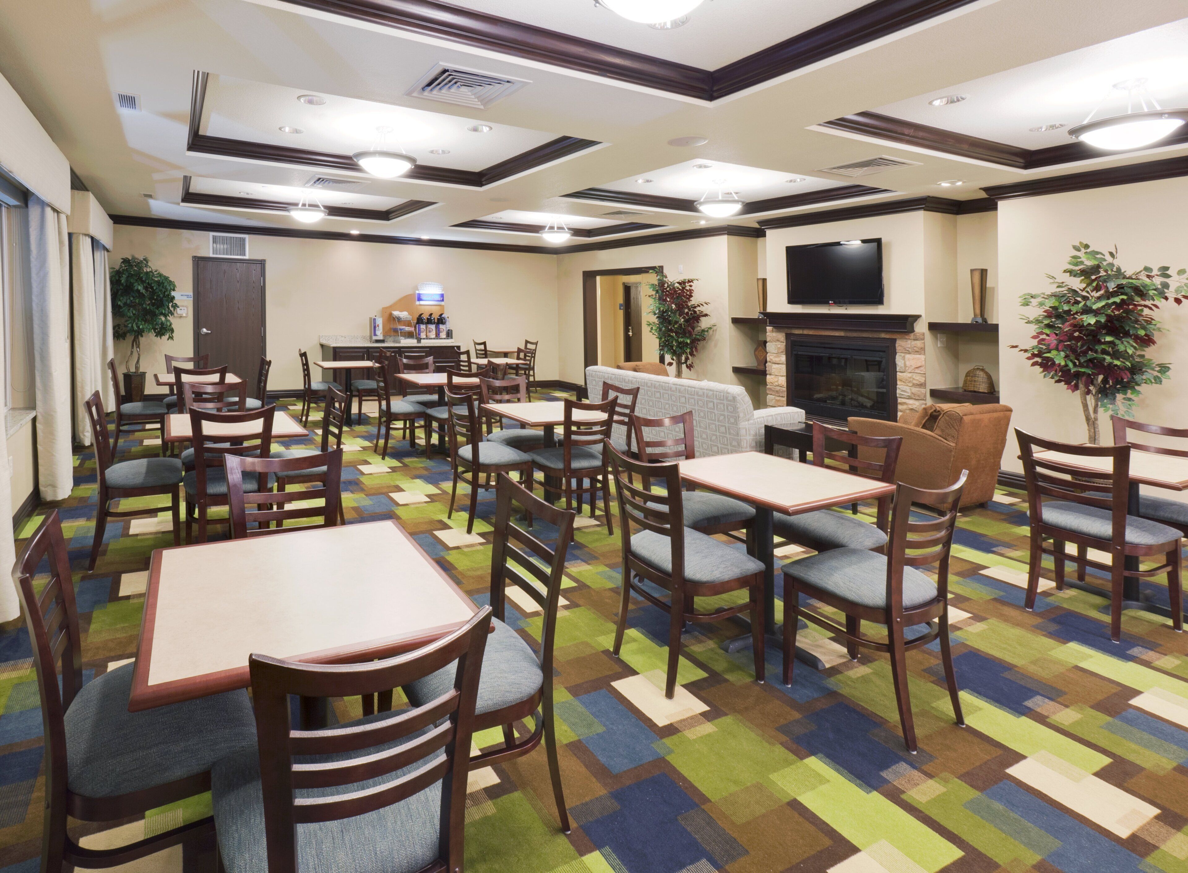 A hotel lobby with multiple seating areas, a fireplace, and a television mounted on the wall.