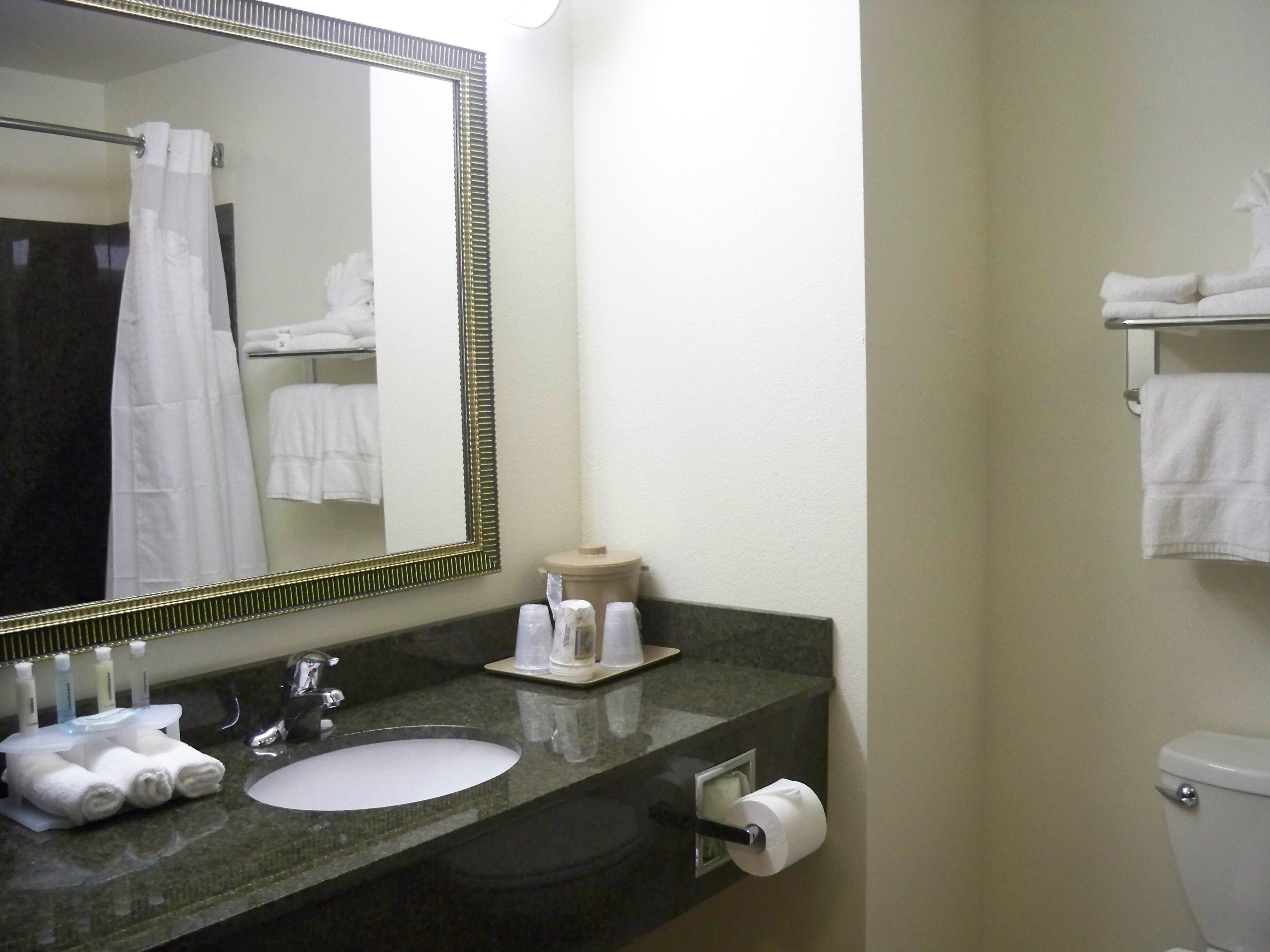 A bathroom with a sink, mirror, toilet, and towel rack.