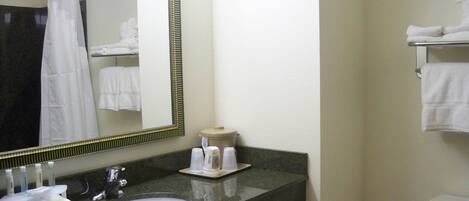 A bathroom with a sink, mirror, toilet, and towel rack.