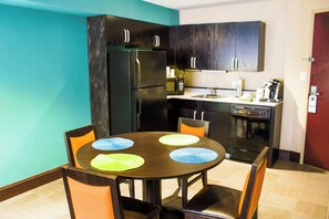 Cocina compacta con armarios de madera oscura, un refrigerador, microondas y lavavajillas.