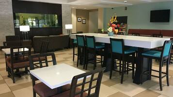 A hotel dining area with multiple tables and chairs, a bar area, and a seating section.