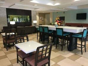 A hotel dining area with multiple tables and chairs, a bar area, and a seating section. - Holiday Inn Express Havelock NW- New Bern by IHG (Havelock)