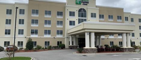 Edificio de Holiday Inn Express con entrada cubierta, varias ventanas y un estacionamiento.