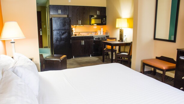 A hotel room with a bed, a desk, a chair, a small table, a bench, a microwave, and a refrigerator. - Holiday Inn Express Havelock NW- New Bern by IHG (Havelock)