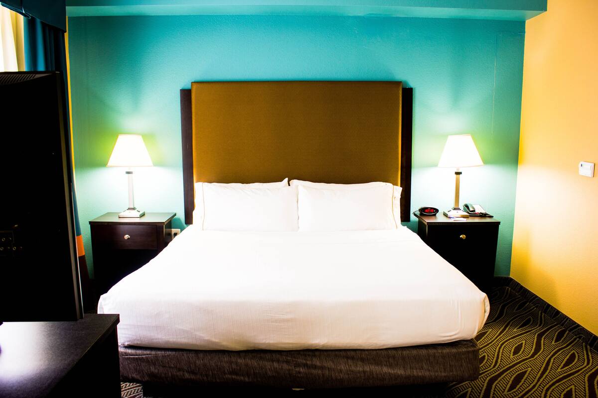 A hotel room with a large bed, two bedside tables with lamps, and a nightstand with a telephone.