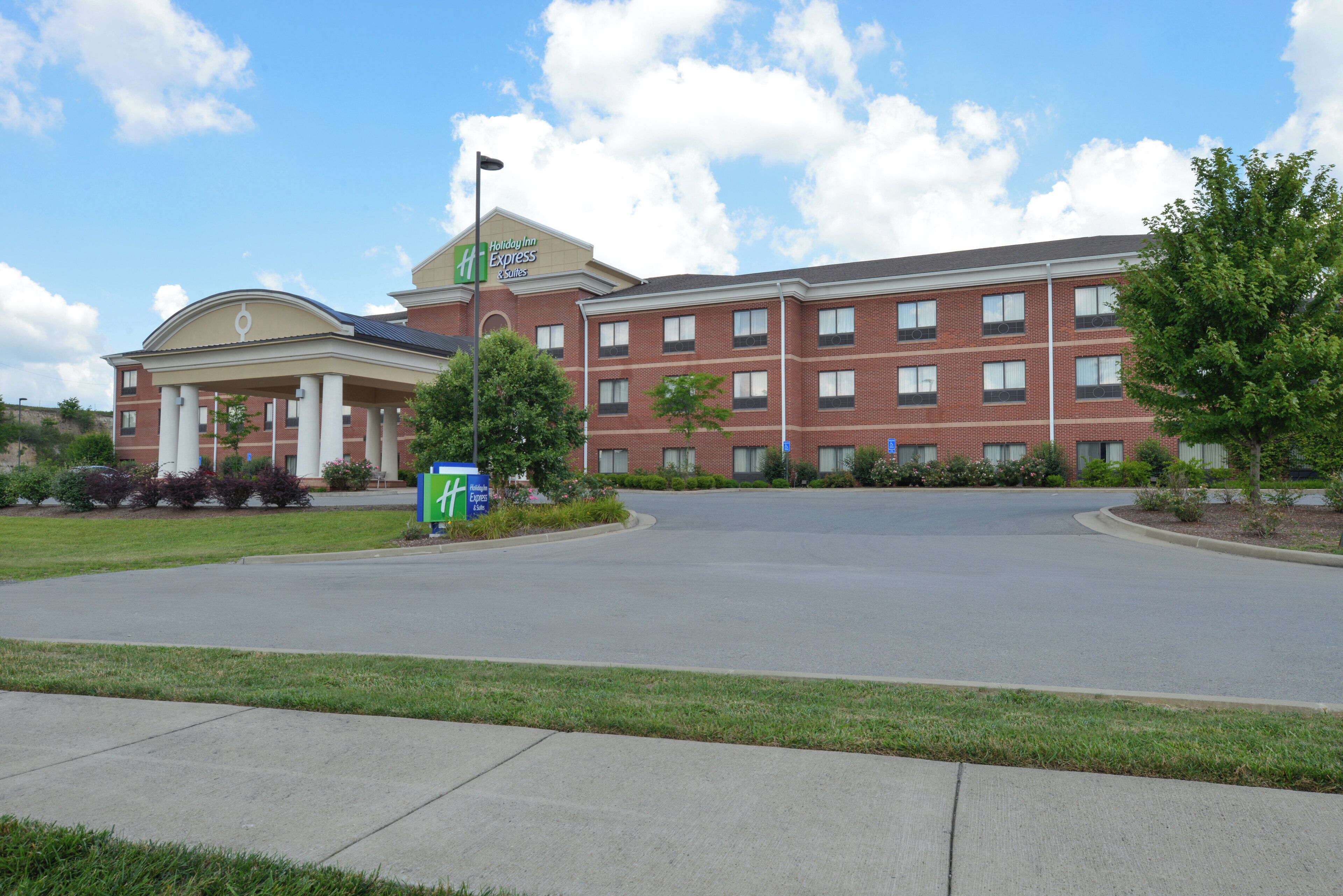 A Holiday Inn Express & Suites hotel with a brick facade, a central entrance, and a parking lot.