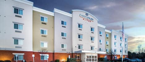 A multi-story hotel with a prominent 'Candlewood Suites' sign, a parking lot with marked spaces, and a brick facade.