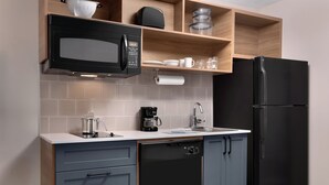 A compact kitchen with a black microwave, coffee maker, and dishwasher.