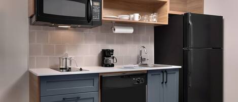 A compact kitchen with a black microwave, coffee maker, and dishwasher.