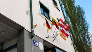 A hotel building with a sign indicating it is a hotel, multiple flags, and a clear blue sky.