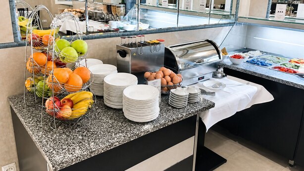A buffet setup with fruits, eggs, and various food items.
