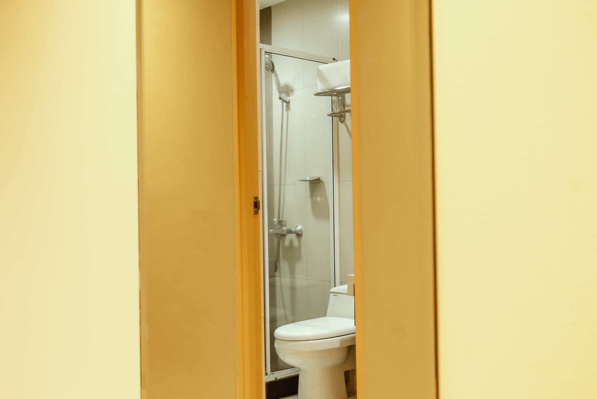 A bathroom with a glass shower enclosure, a white toilet, and a towel rack.