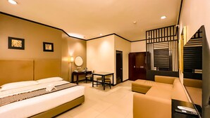 A hotel room with a bed, a desk, a chair, a sofa, and a TV. - Casa Bocobo Hotel (Manila)