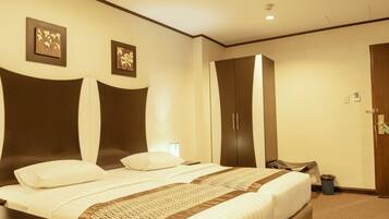Habitación de hotel con una cama grande, un armario y dos obras de arte colgadas en la pared.