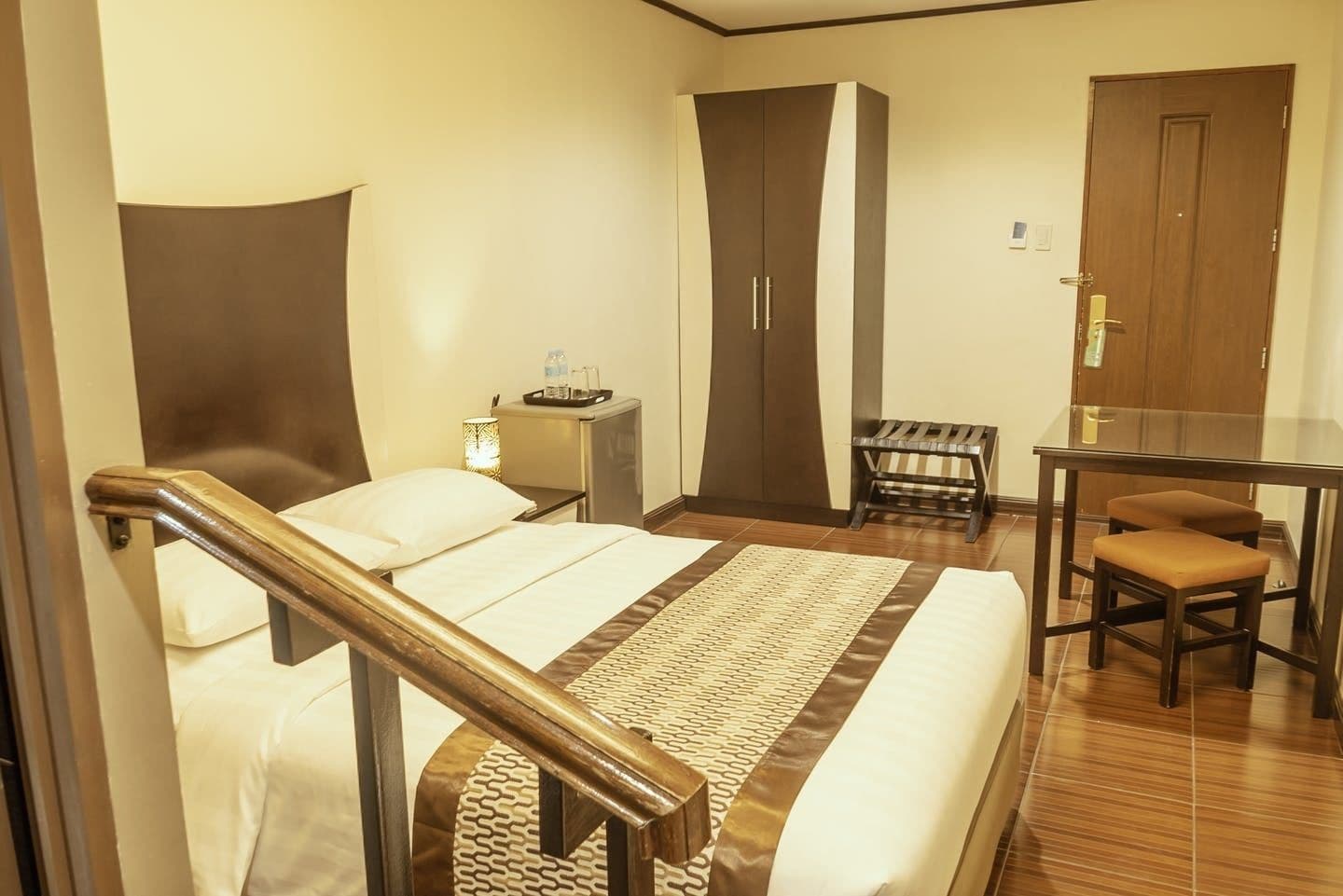 A hotel room with a bed, a desk, a chair, and a wardrobe.