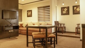 A modern living room with a sofa, a coffee table, and a TV mounted on the wall. - Casa Bocobo Hotel (Manila)