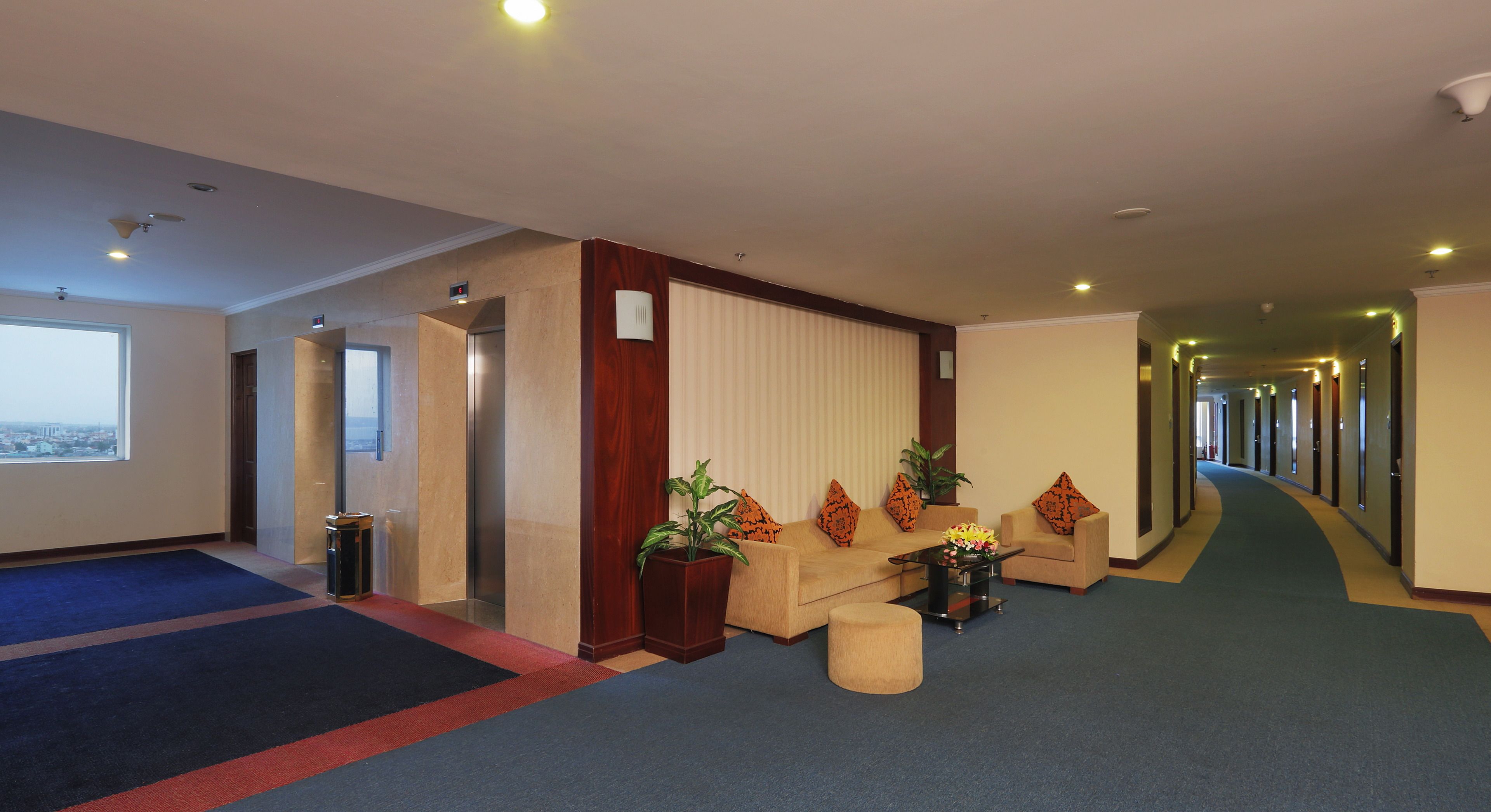 Un vestíbulo de hotel con mostrador de recepción, zona de estar y vistas a la ciudad.