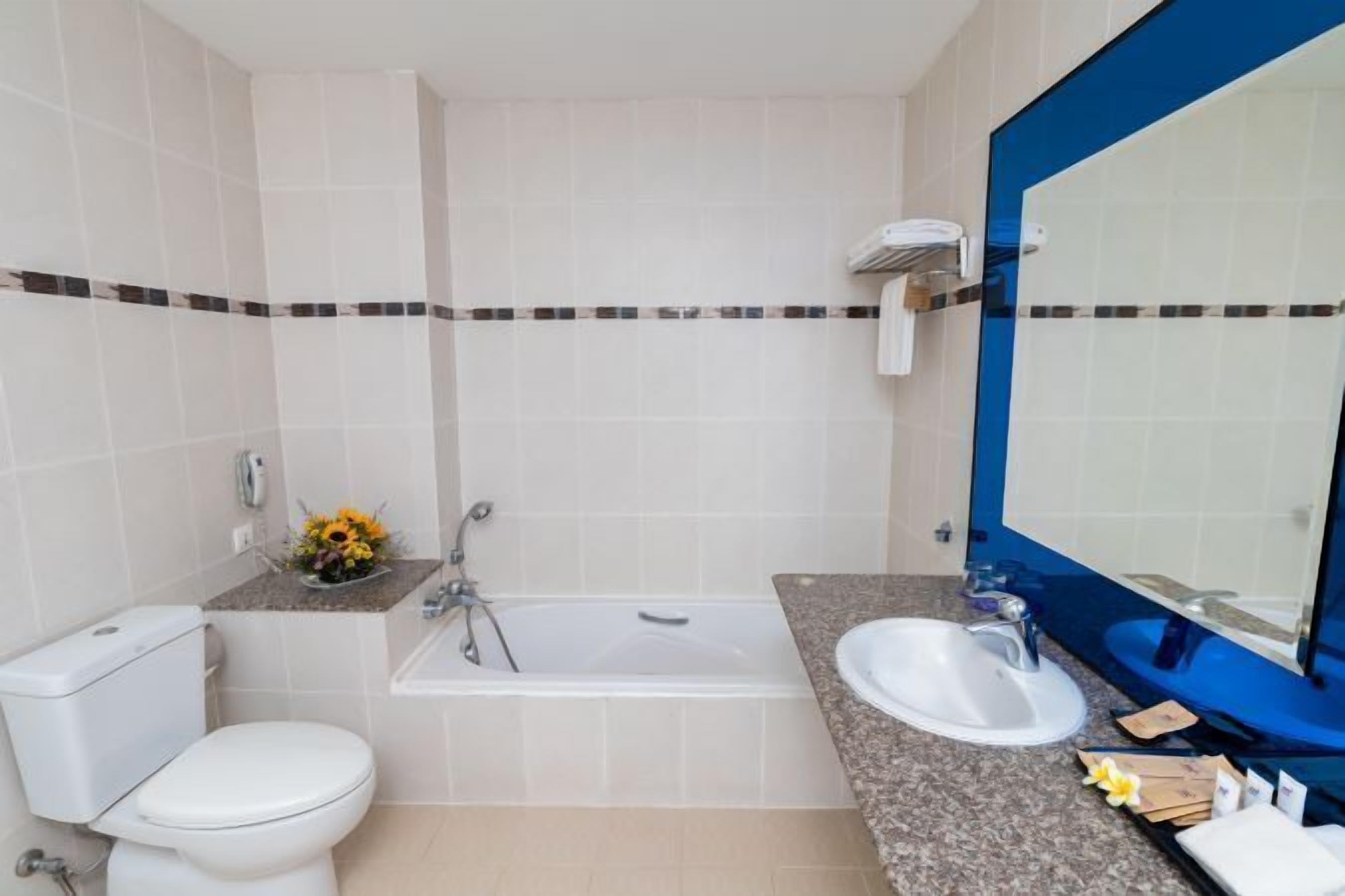 A bathroom with a toilet, a bathtub, a sink, and a large mirror.