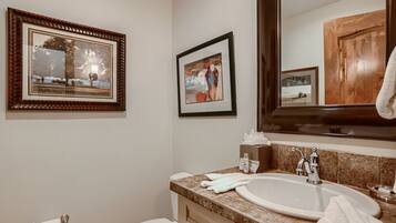 A bathroom with a sink, mirror, and two framed pictures on the wall.