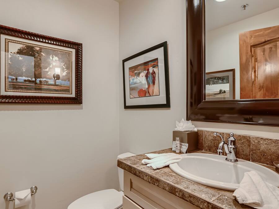 A bathroom with a sink, mirror, and two framed pictures on the wall.