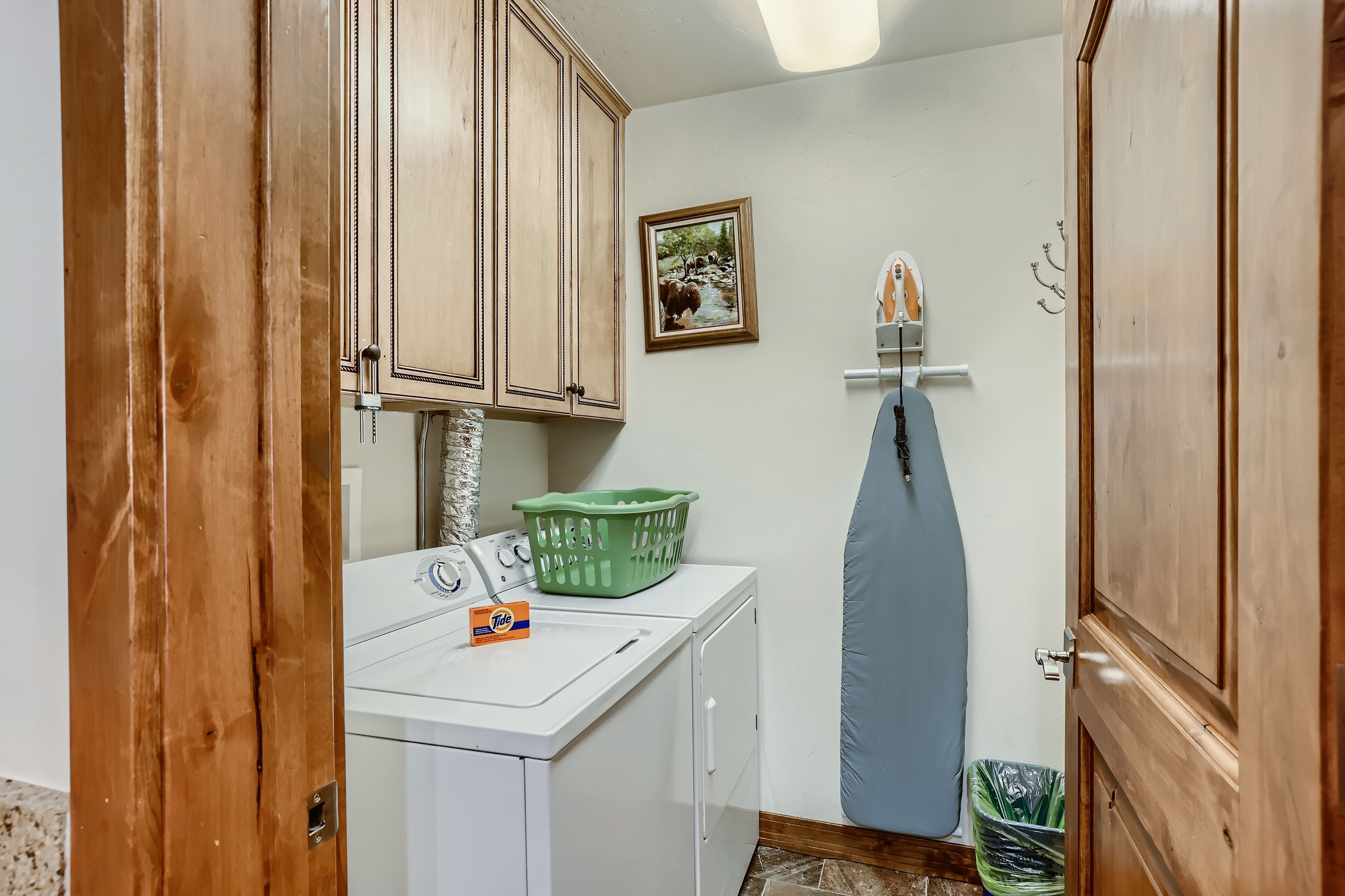 A laundry area with a washing machine, a green laundry basket, and a hanging clothes rack.