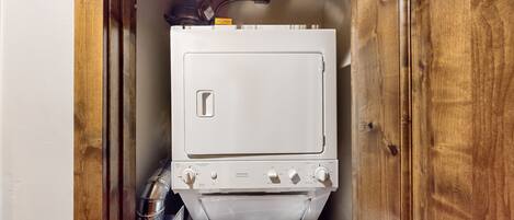 A compact, white, wall-mounted washing machine with a front-loading door and control knobs.