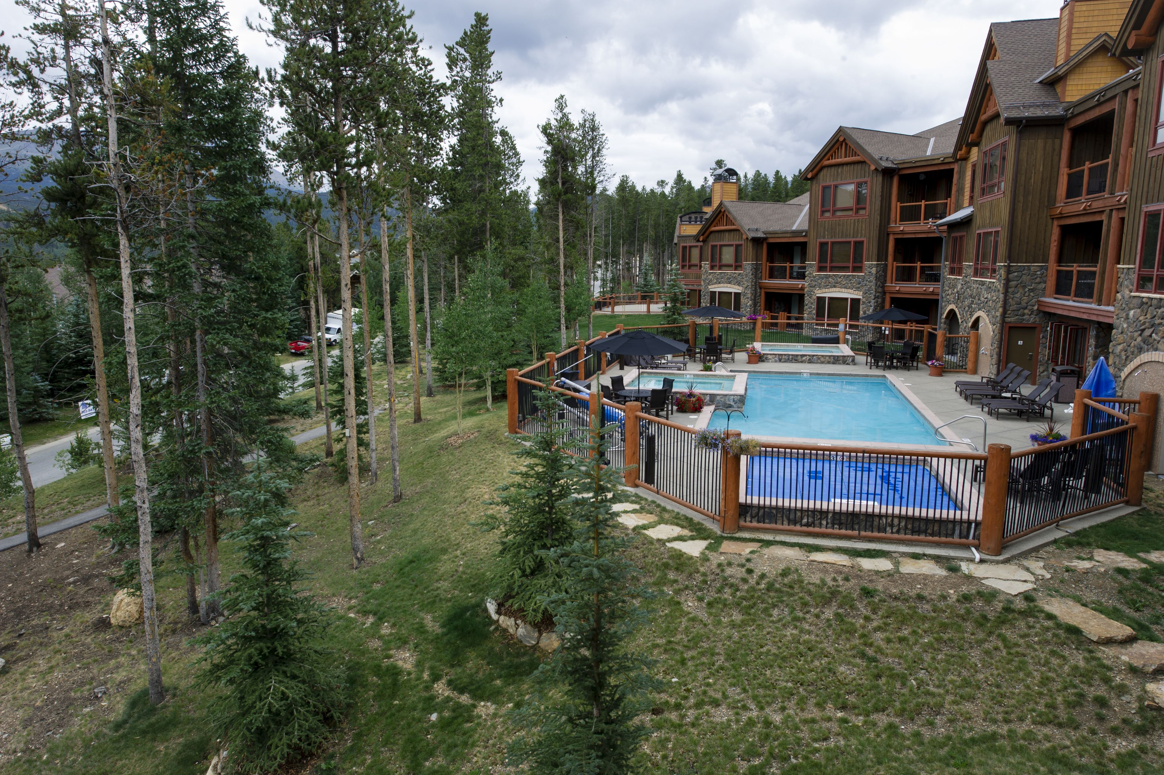 A resort with a swimming pool, outdoor seating, and a view of the surrounding forest.