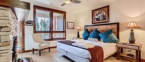 A bedroom with a bed, a chair, a nightstand, a lamp, and a ceiling fan.