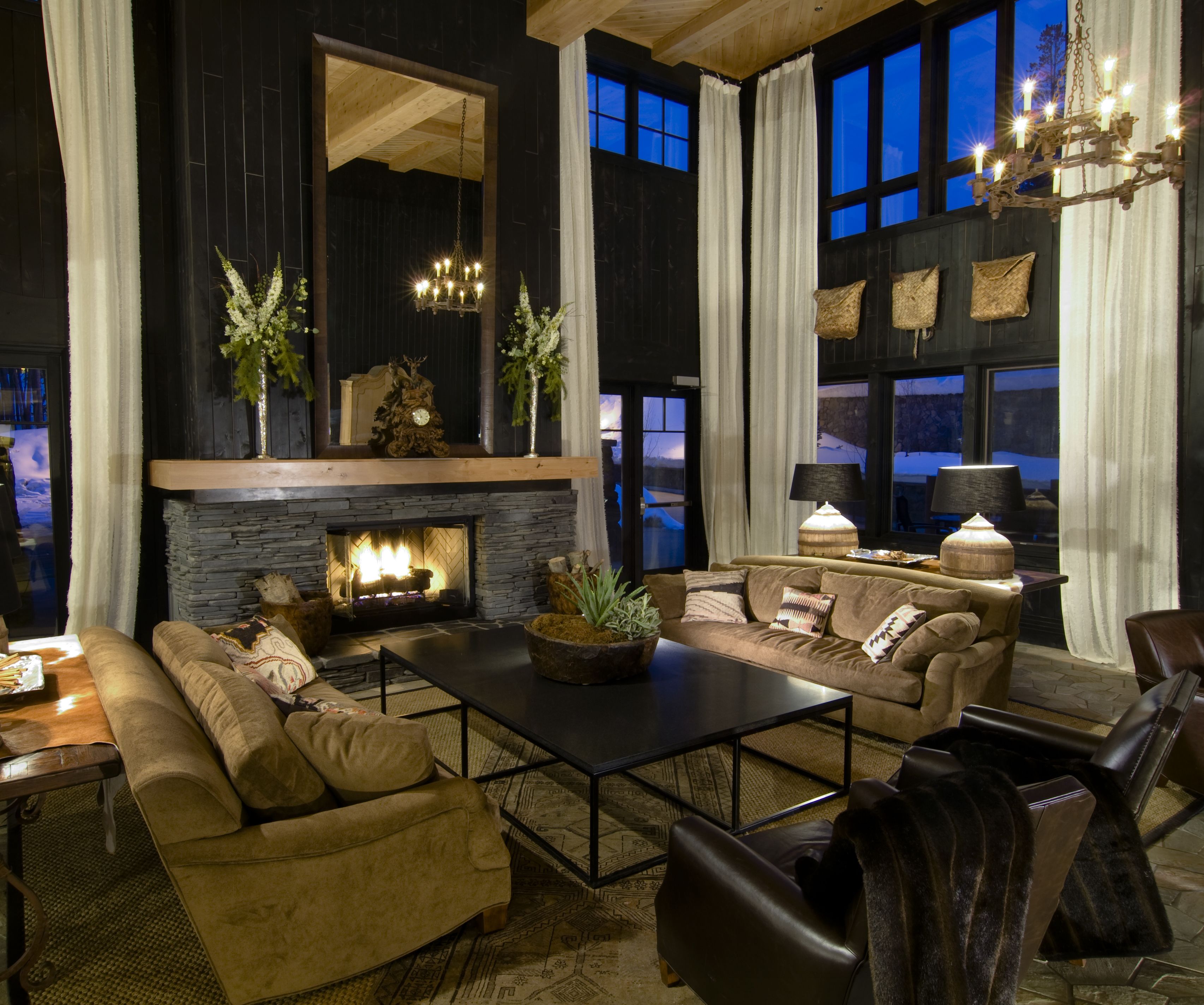 A cozy living room with a fireplace, comfortable seating, and large windows.