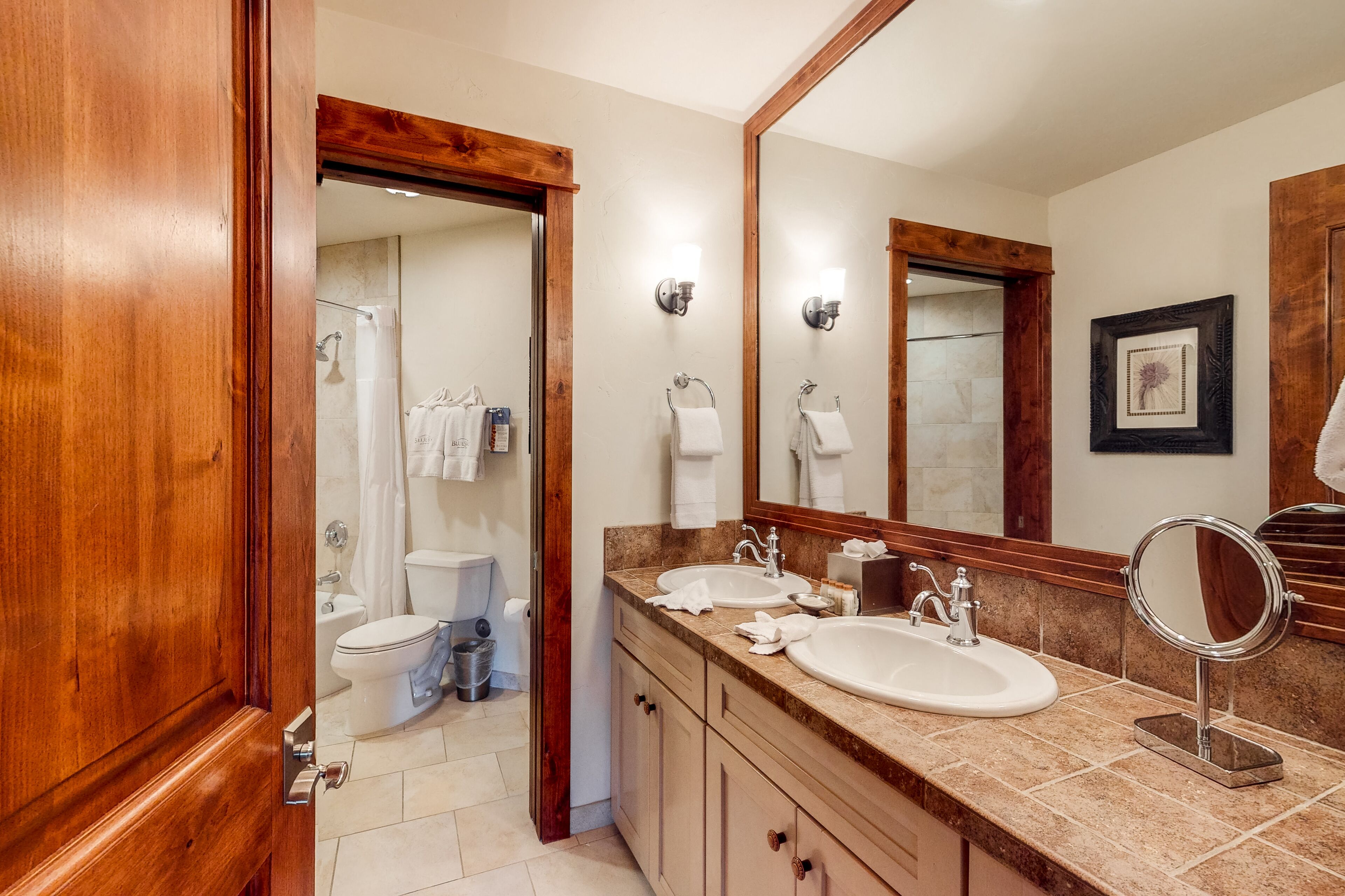 Une salle de bain avec deux lavabos, un grand miroir et des meubles en bois.