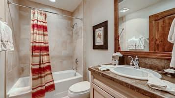 A bathroom with a bathtub, toilet, sink, and shower curtain.