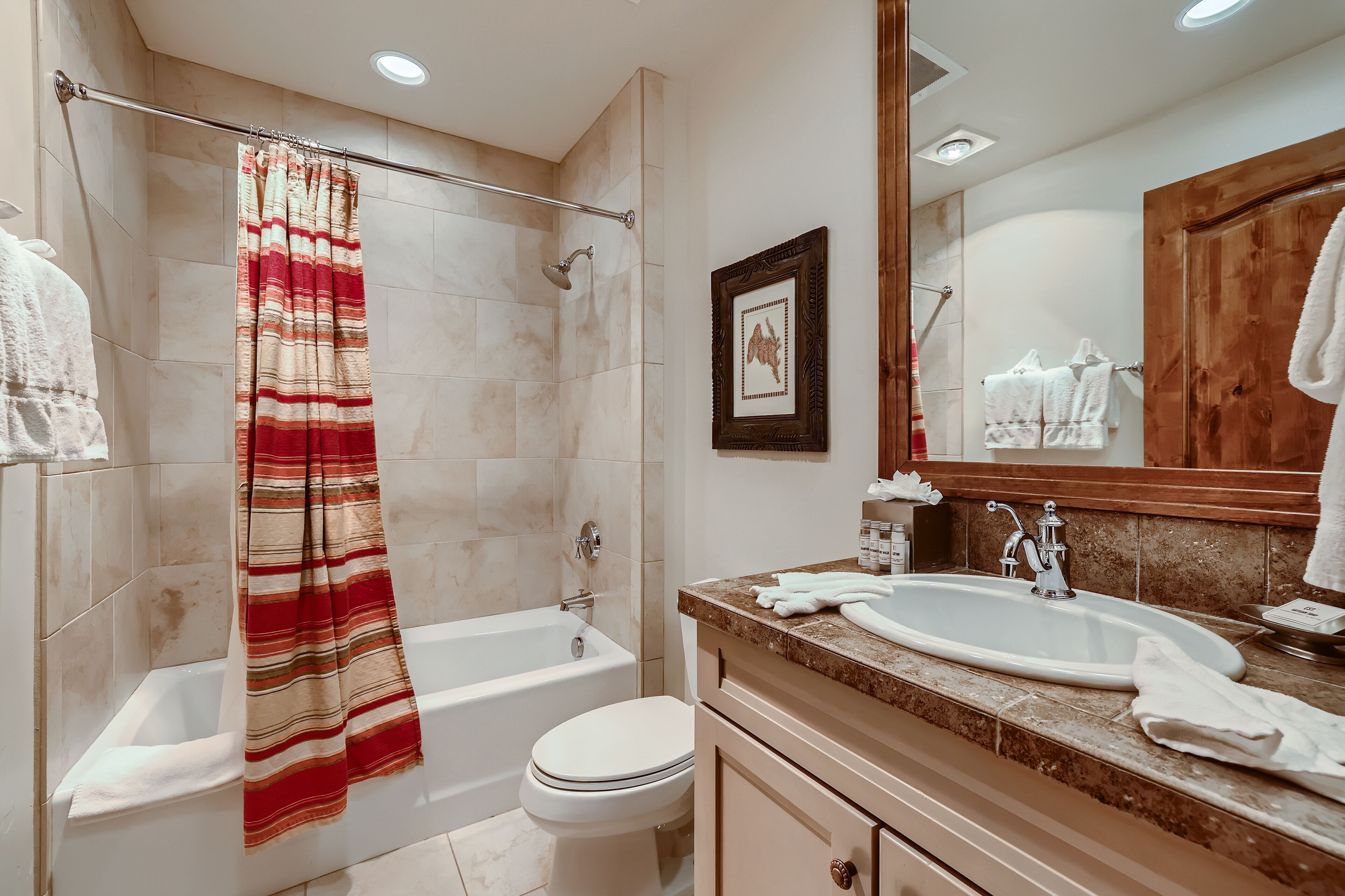 A bathroom with a bathtub, toilet, sink, and shower curtain.