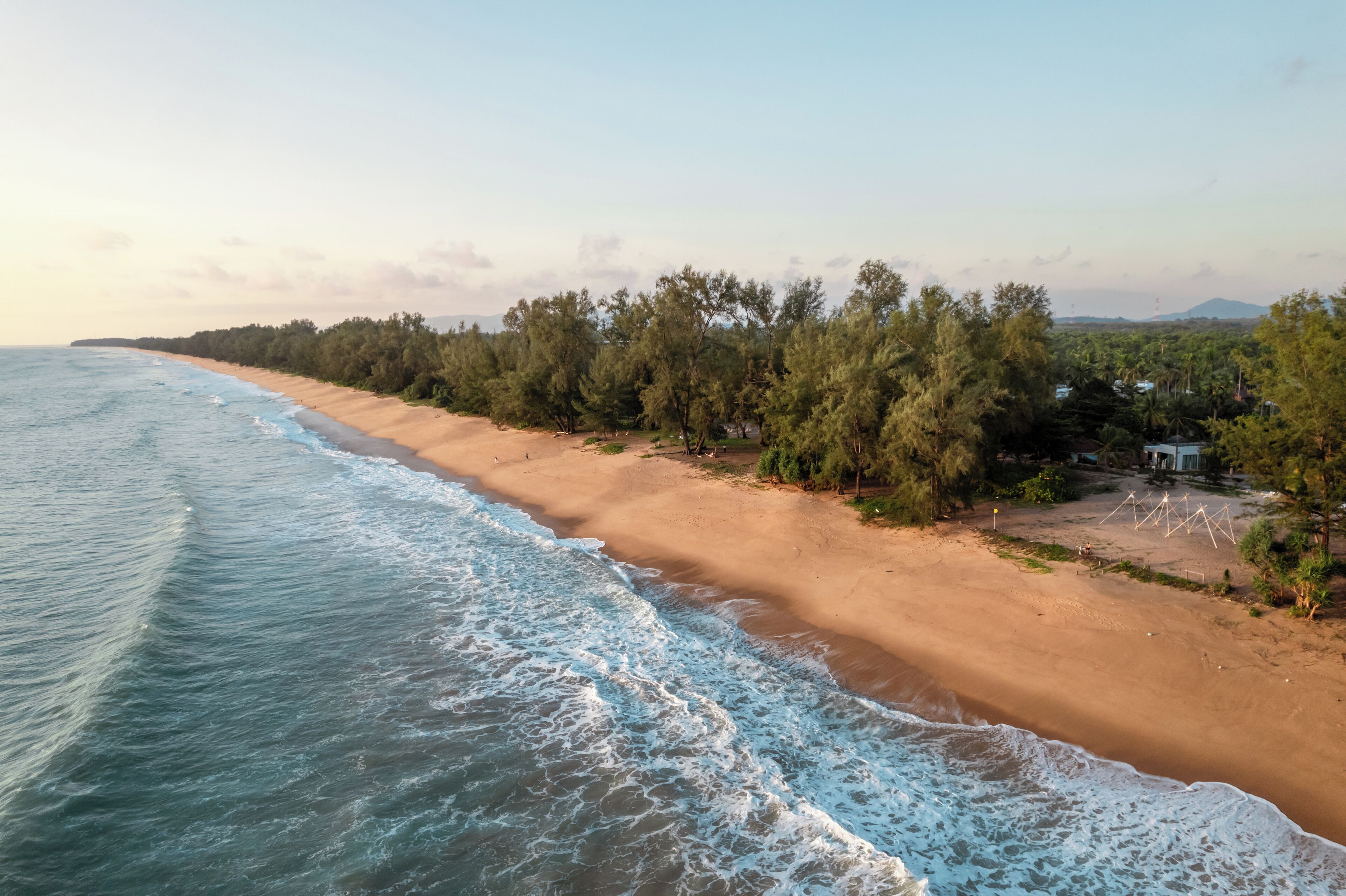 A beach with a sandy shore, trees, and a small structure.