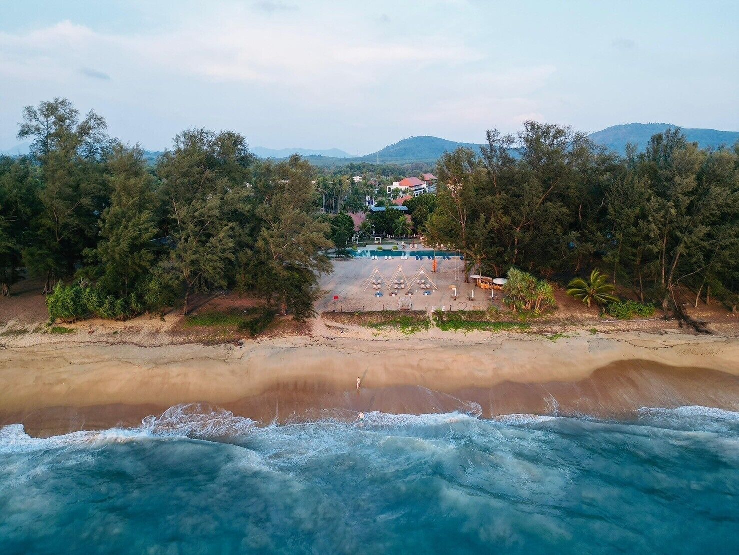 Un resort en la playa con piscina, sillones de descanso y vista al océano.