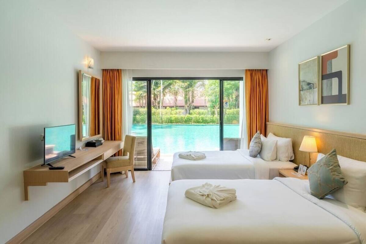 Habitación de hotel con cama, escritorio, televisión y vista a una piscina.