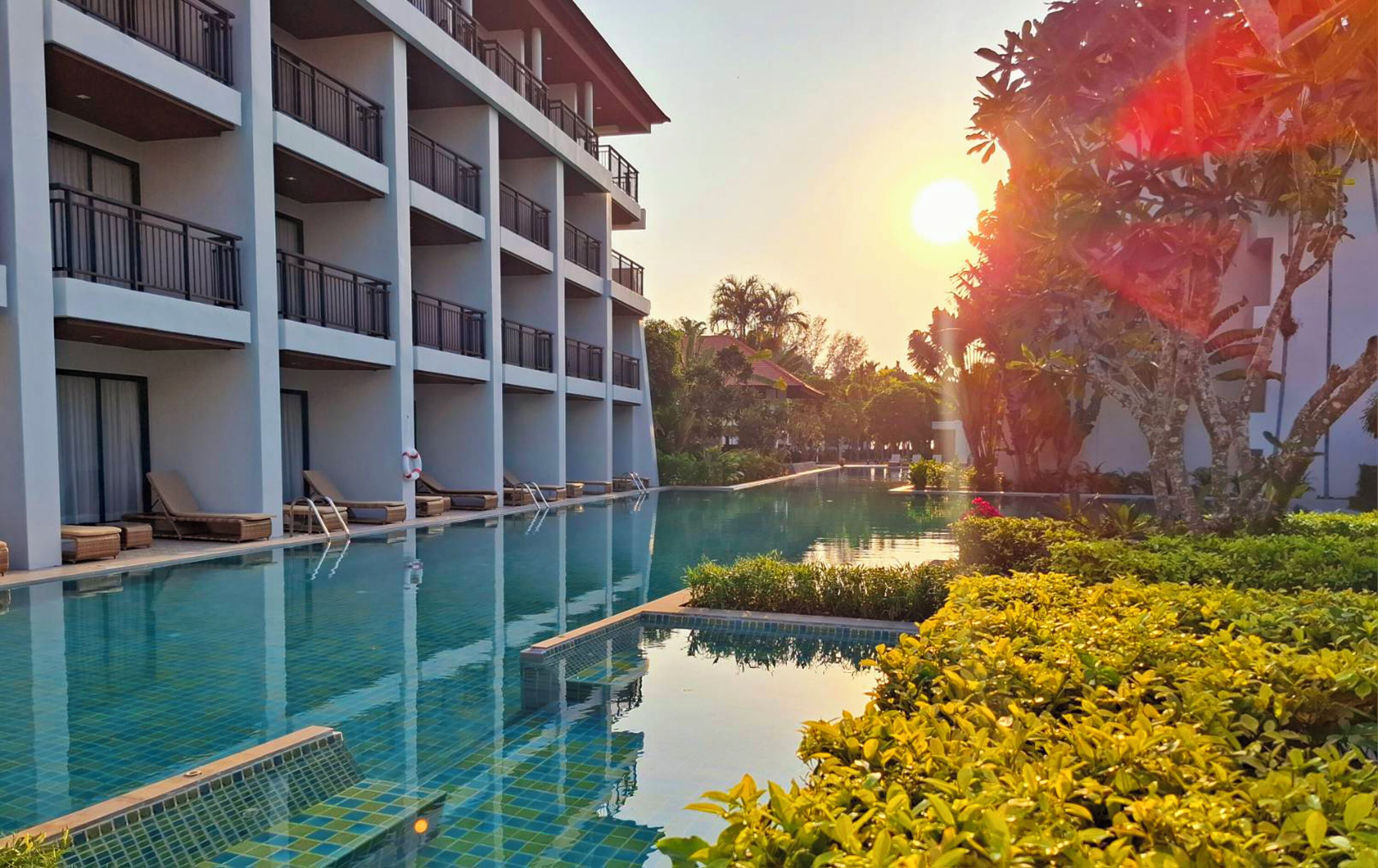 Ein Hotel mit Pool, mehreren Balkonen und üppiger Bepflanzung.