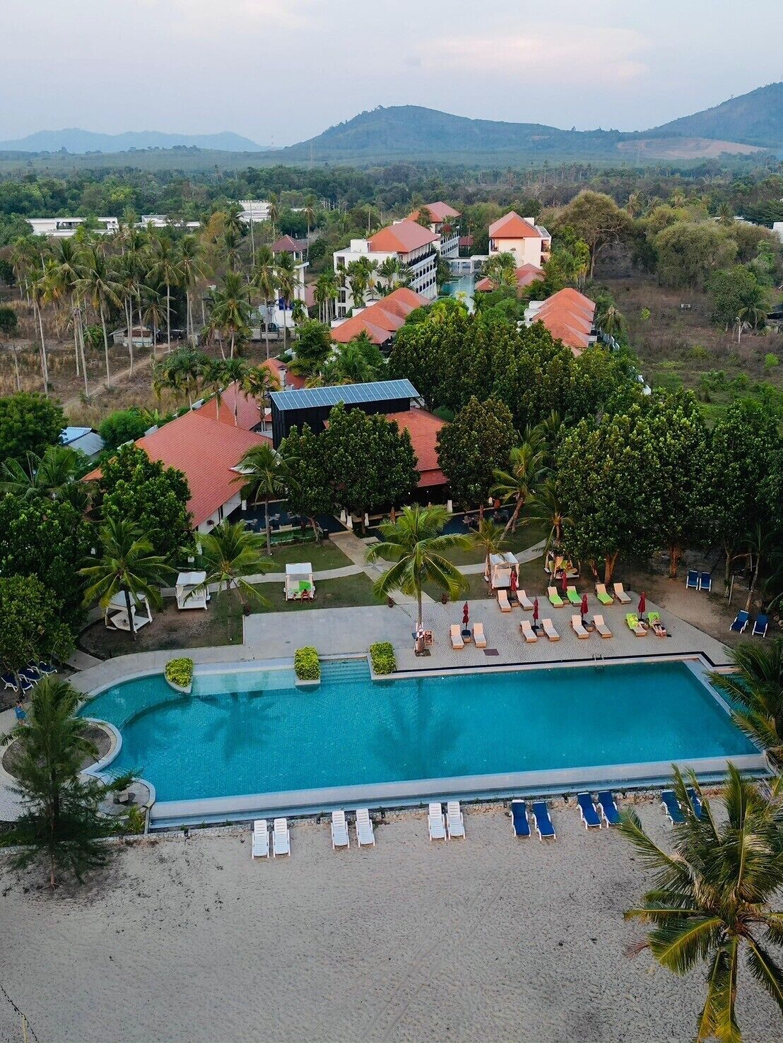 A resort with a swimming pool, lounge chairs, and a view of the surrounding landscape.