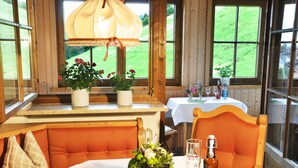 Un coin repas chaleureux, avec des meubles en bois, une table dressée avec une bouteille, des verres et un vase de fleurs.