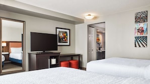 A hotel room with two beds, a TV, a desk, and a mirror.