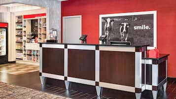 A reception desk with a red wall and a poster of cows.