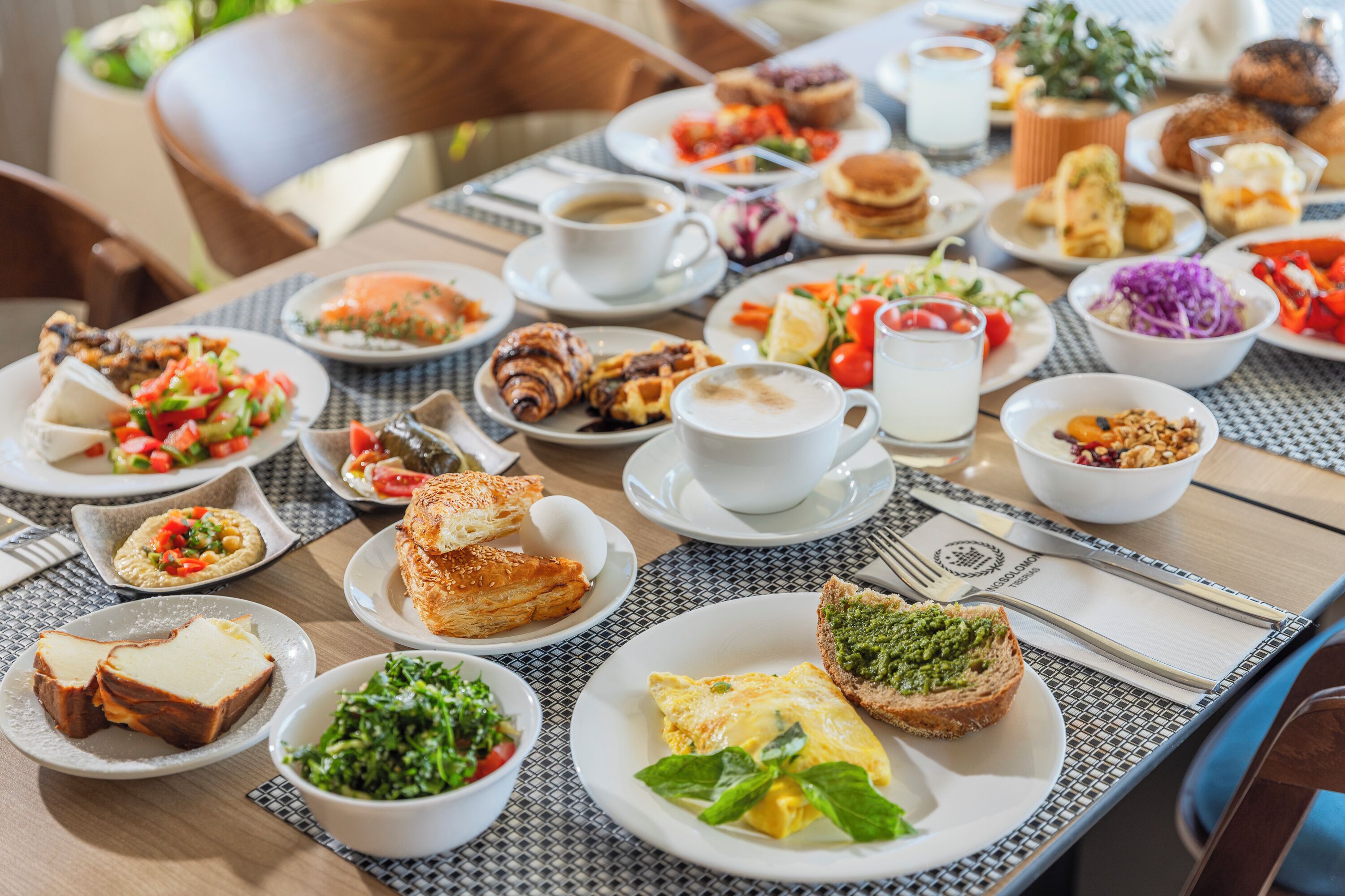 A breakfast buffet with various dishes, including eggs, pastries, and salads.