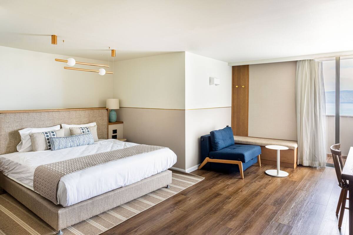 Habitación de hotel con una cama grande, un área de estar con una mesita y vistas al exterior.