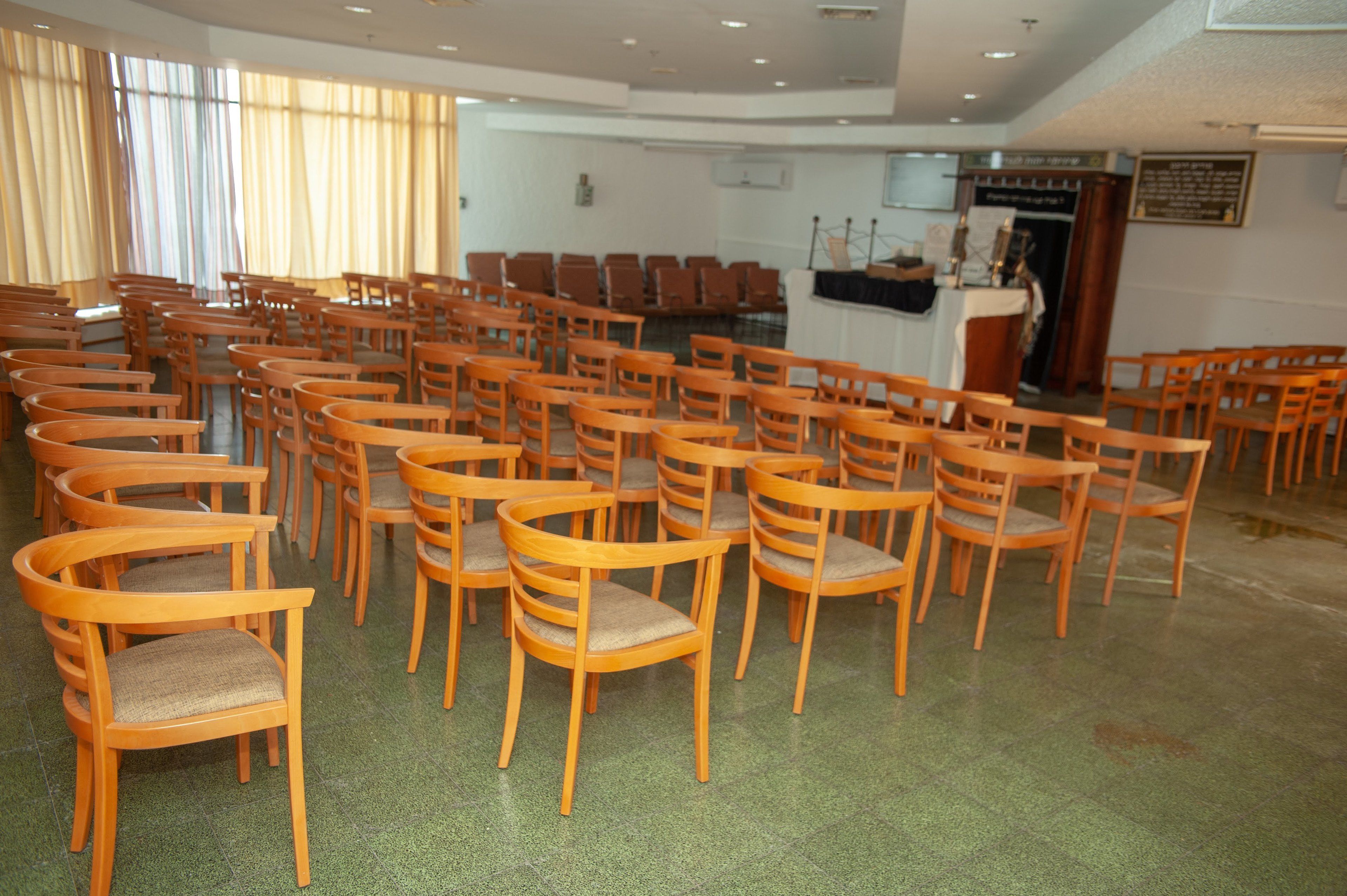A conference room with rows of wooden chairs and a podium at the front.