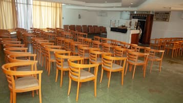 A conference room with rows of wooden chairs and a podium at the front.