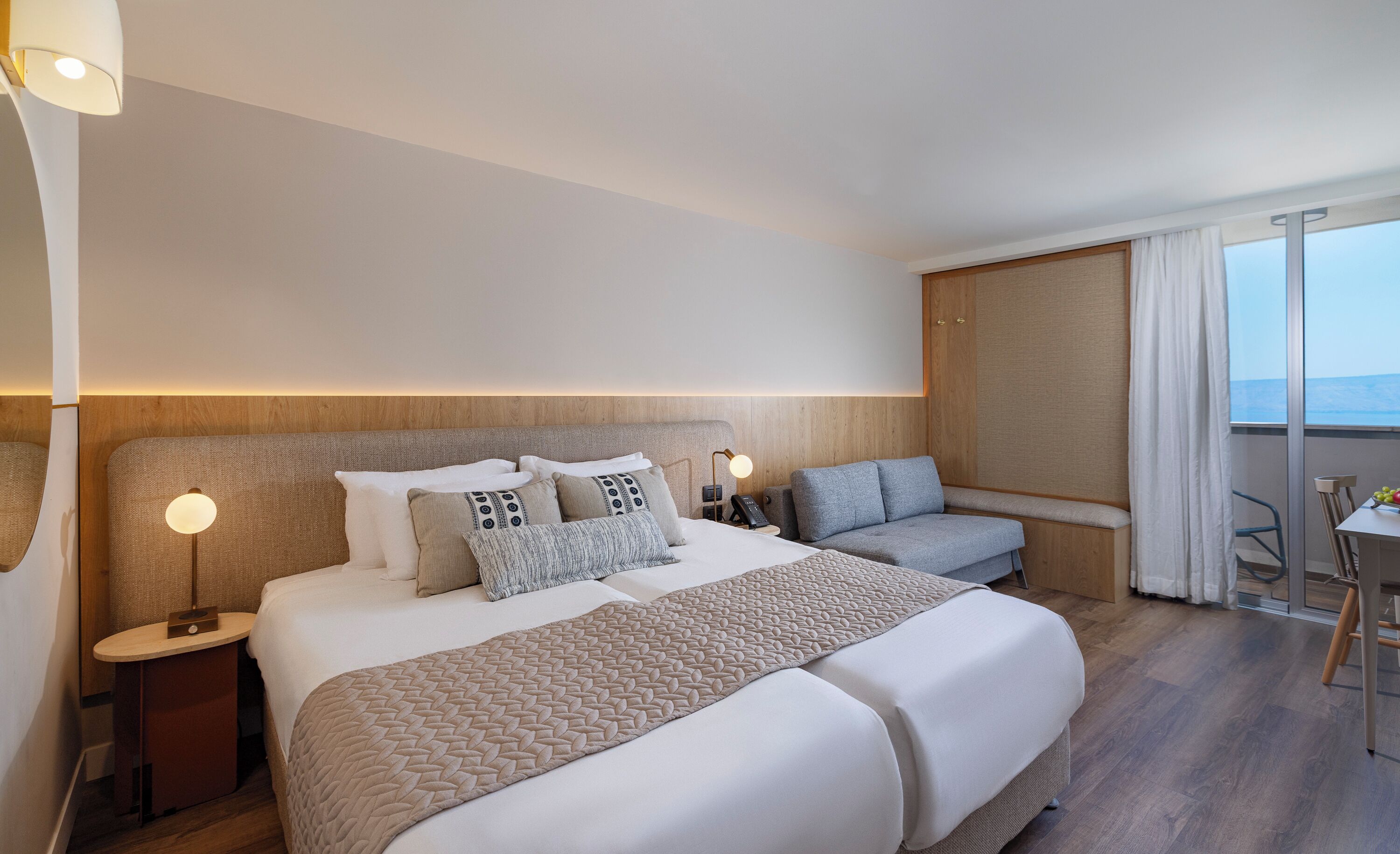 Habitación de hotel con una cama grande, un sofá, un escritorio y vista al mar.